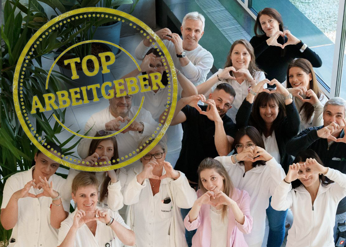 Top Arbeitgeber - lächelnde Mitarbeiter:innen zeigen mit Händen Herzchen
