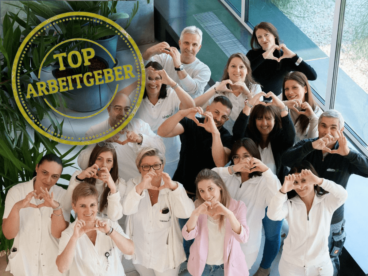 Top Arbeitgeber - lächelnde Mitarbeiter:innen zeigen mit Händen Herzchen