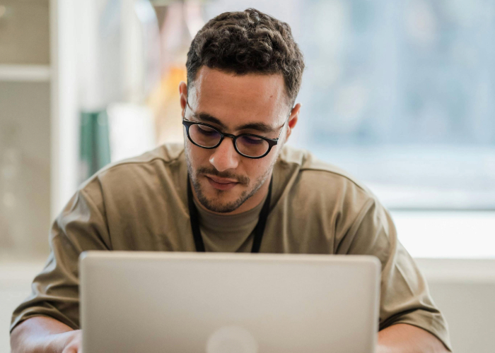 Junger Mann sitzt am Laptop in Ordination.