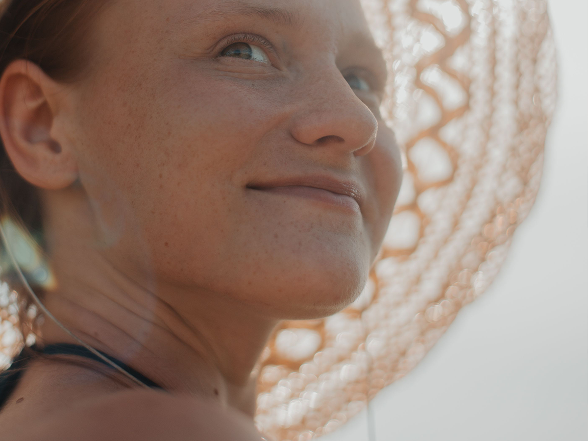 Frau mit Sonnenhut schaut positiv in die Entfernung